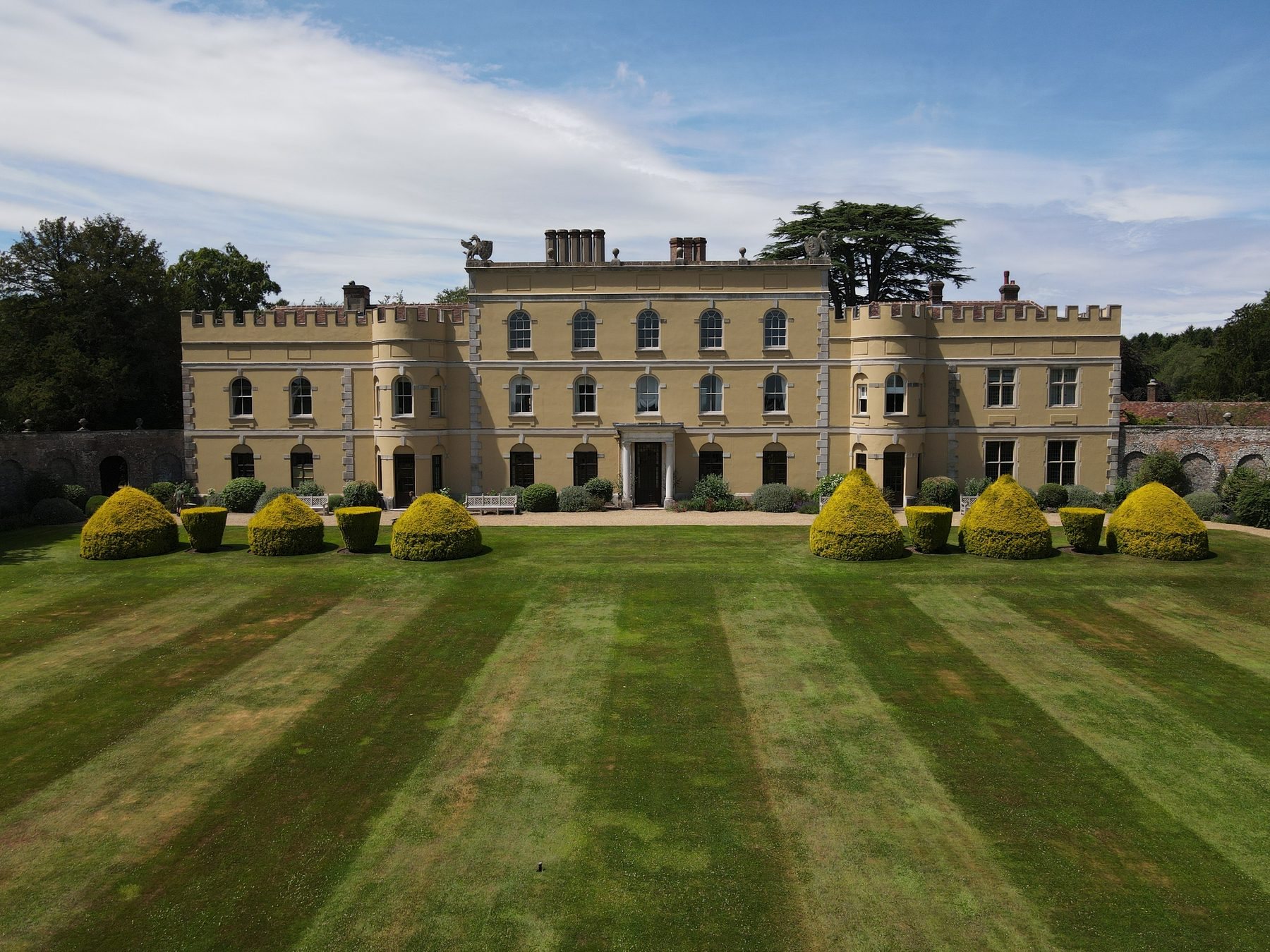 Garden front of Hampden House with crenellated wings and clipped yew topiary