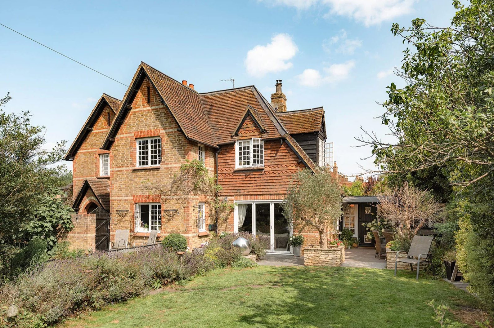Brick and tile-hung cottage seen across the rear lawn