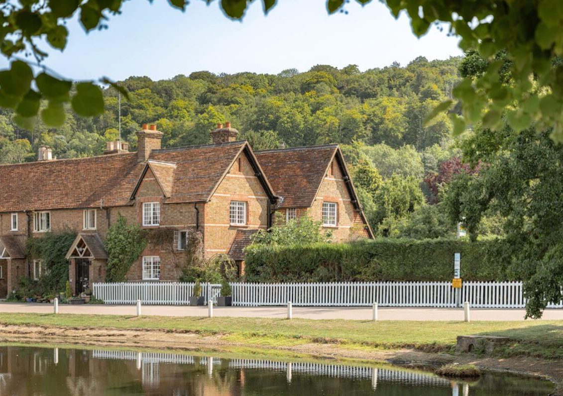 Row of brick and timber-framed cottages beside the village pond in Aldbury