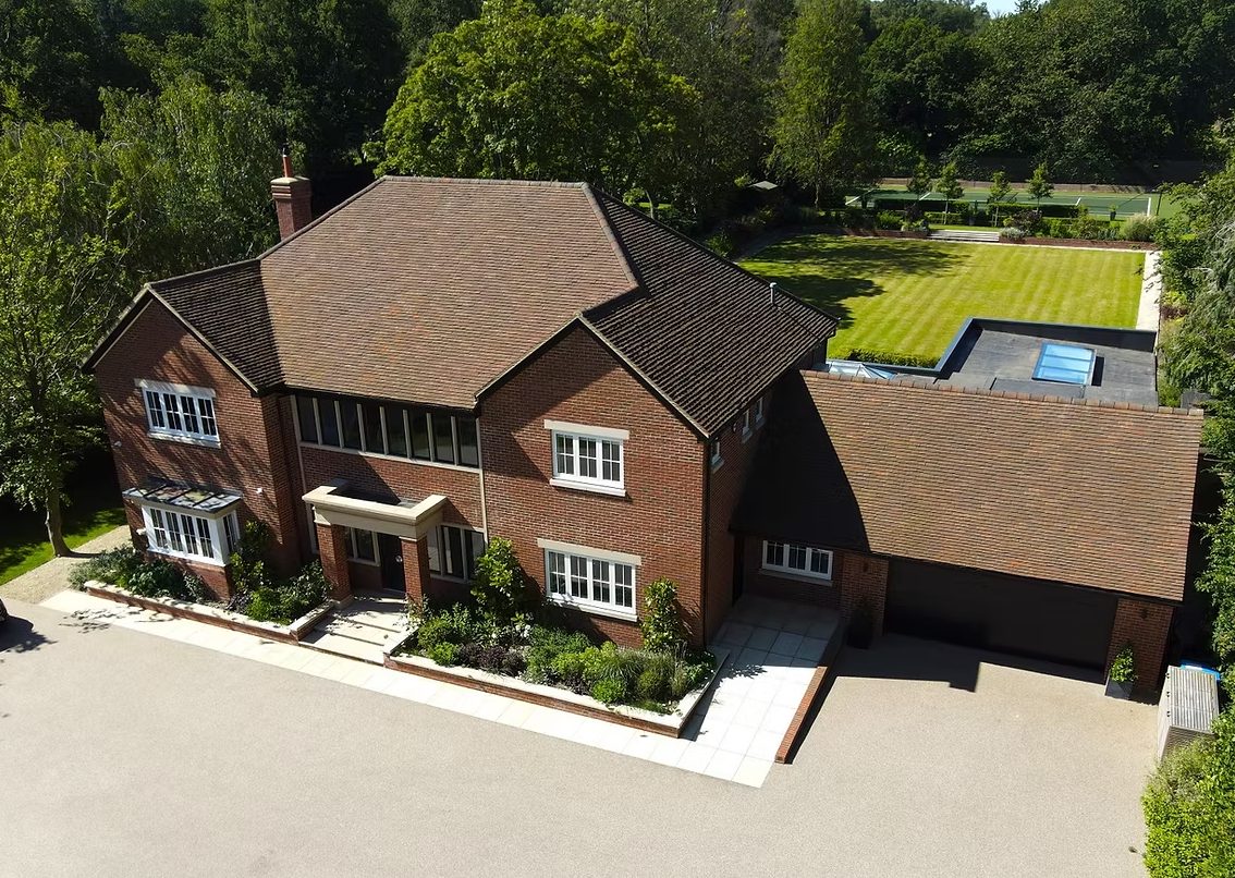 Aerial view of the new brick house with clay tile roofs, garage wing and resin drive