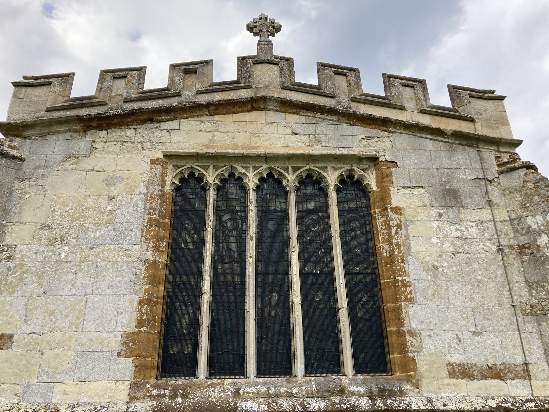 East window with five-light tracery and a crenellated parapet with a cross finial