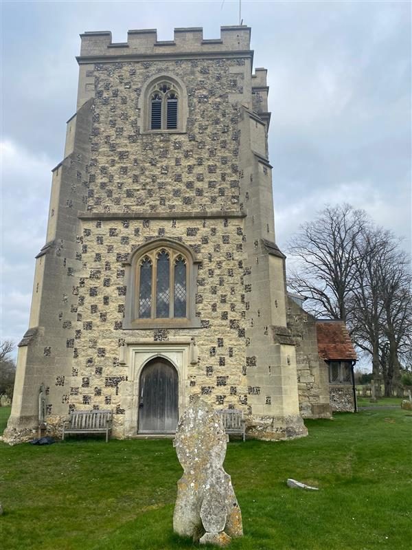 Flint and stone chequerwork tower with a crenellated parapet and an oak west door