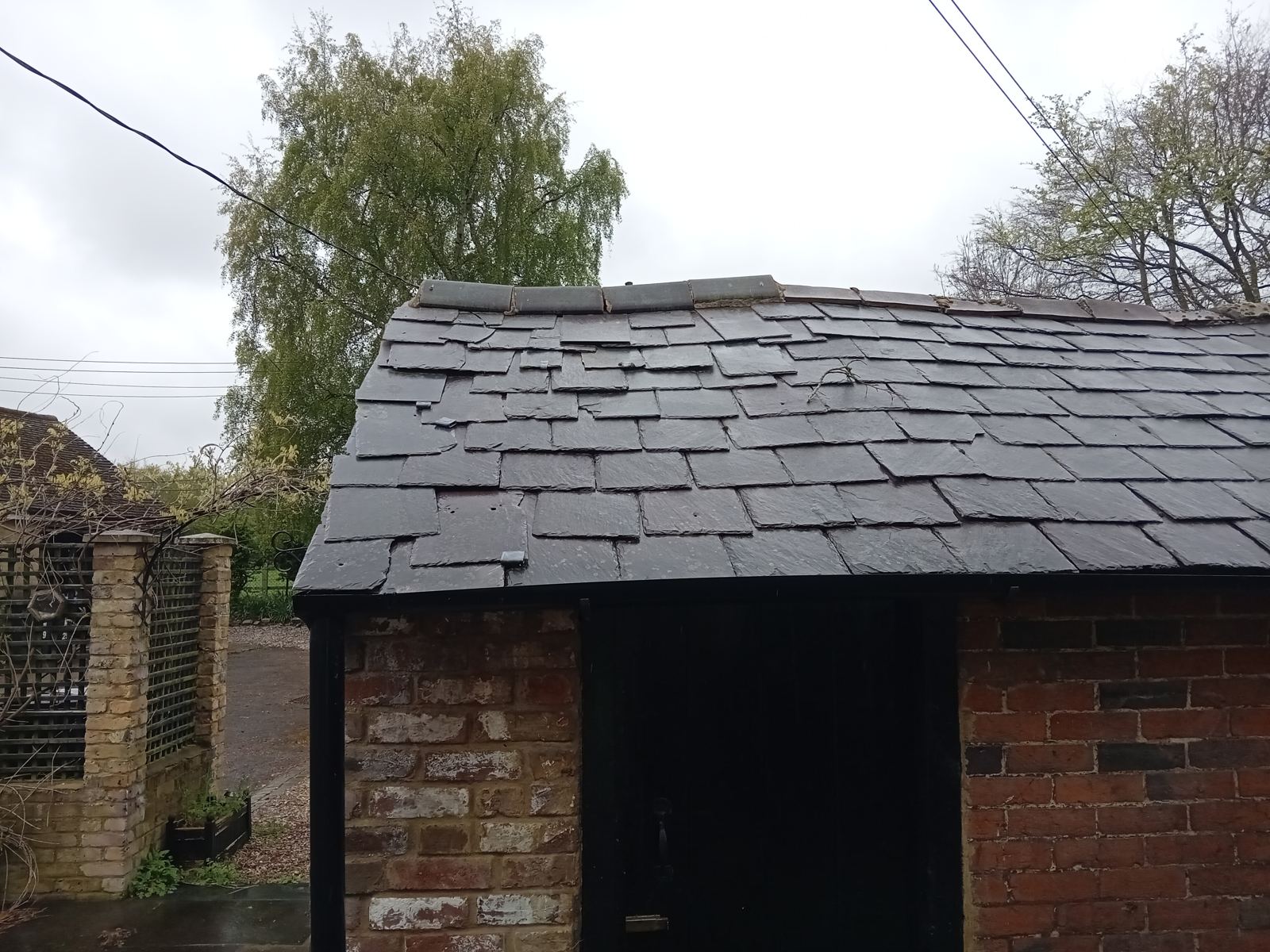Outbuilding roof with slipped and patched slates and mismatched ridge tiles, photo 2 of 2