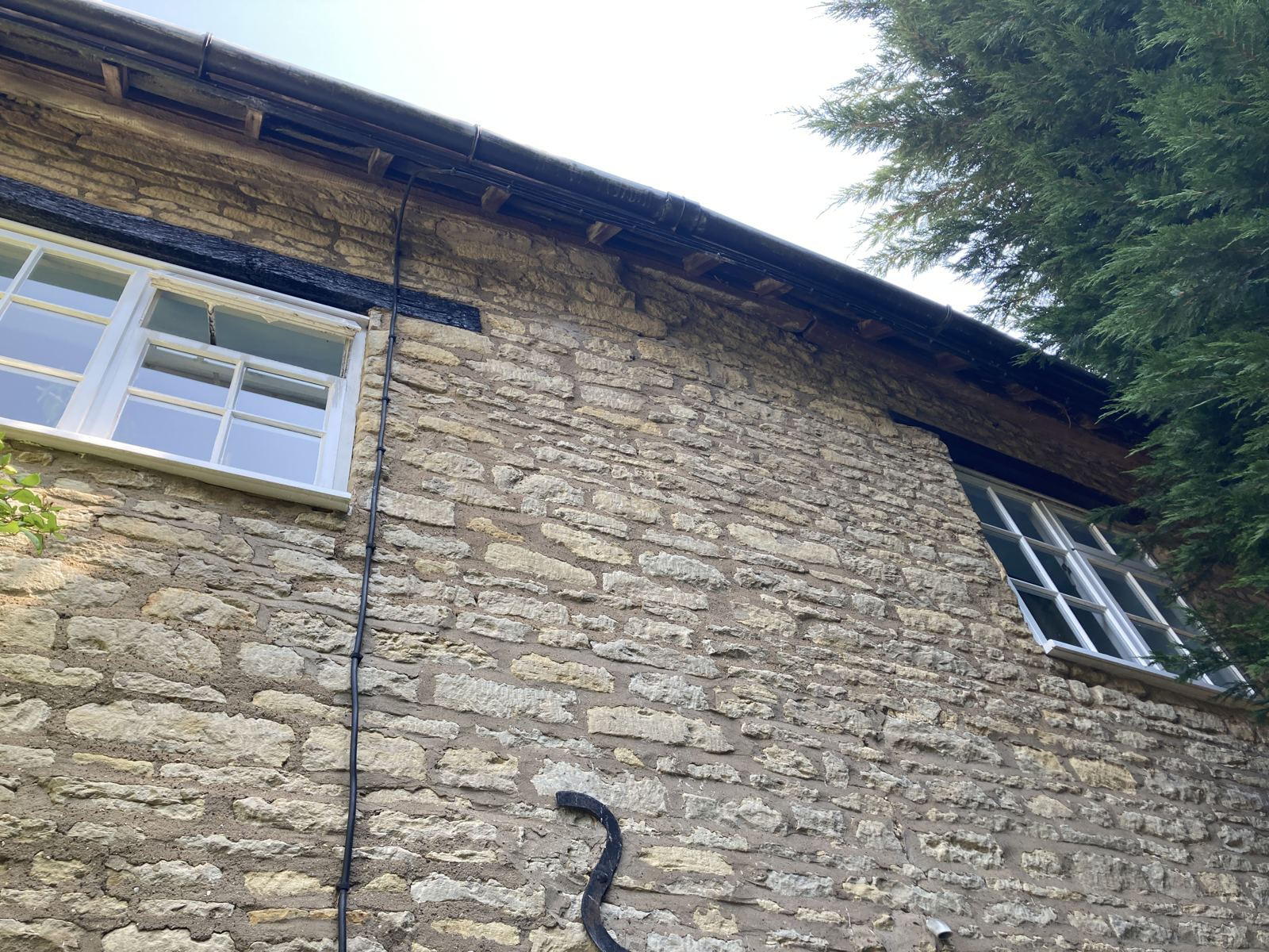 Stone elevation with open joints and a decayed timber lintel below the eaves, photo 3 of 4