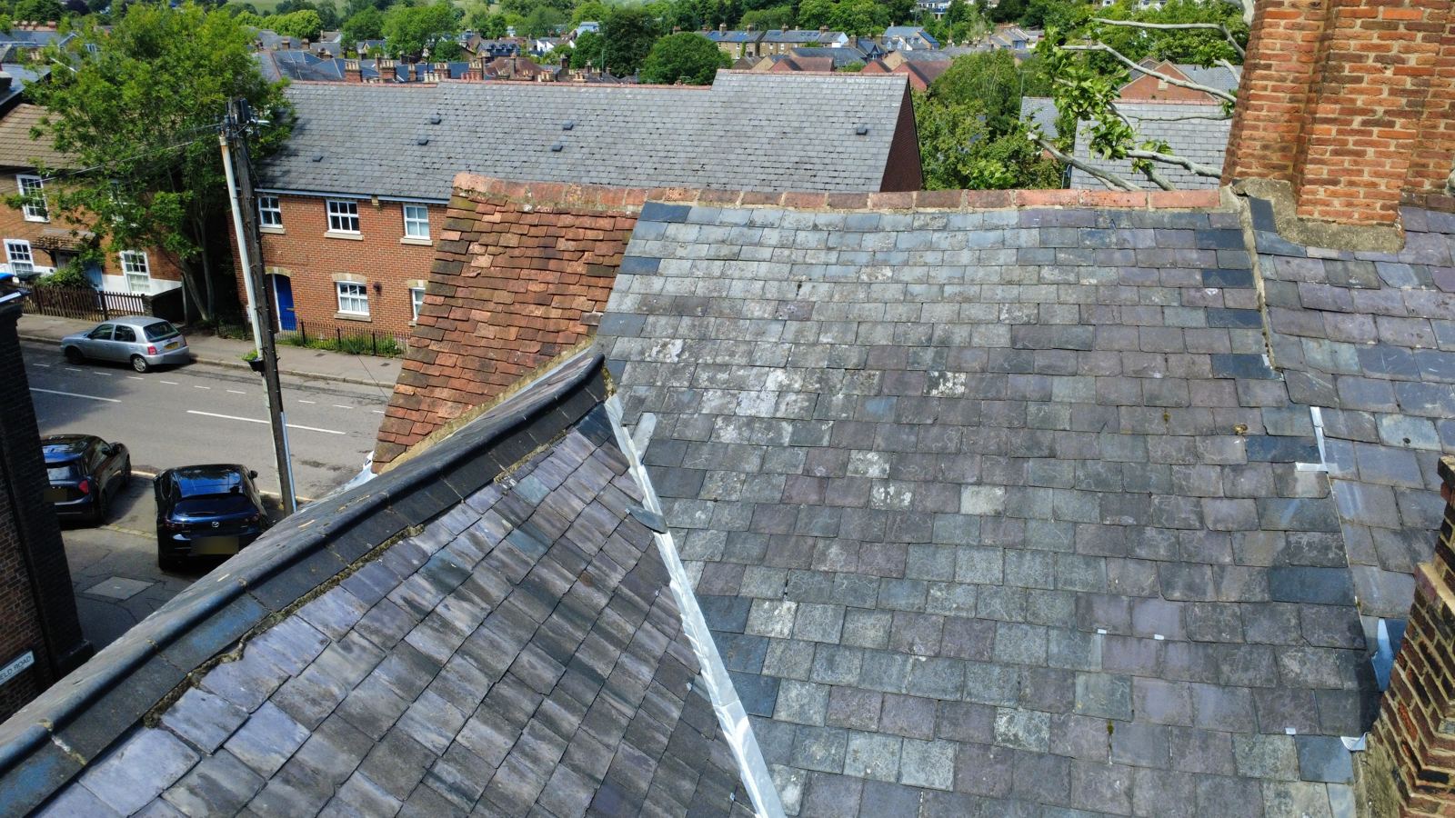 Drone view of slate and clay tile roofs with lead valleys and a worn ridge, photo 3 of 3