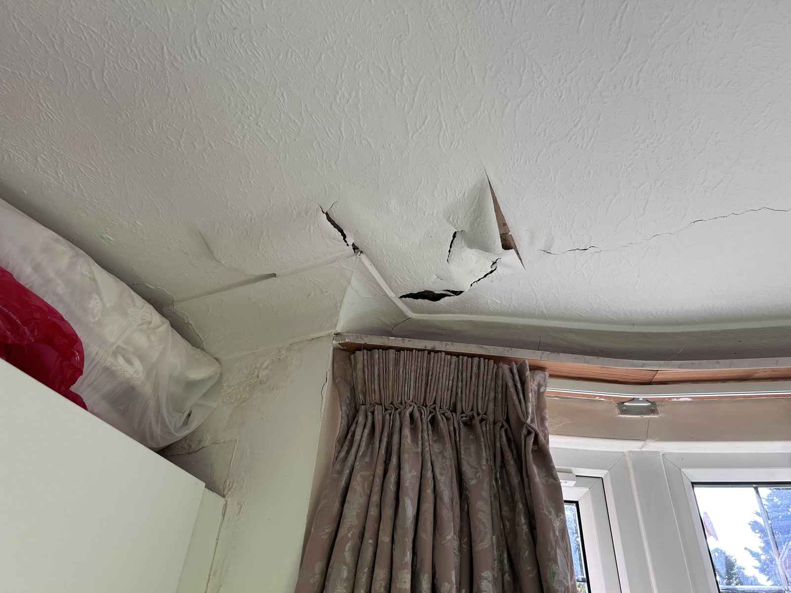 Cracked ceiling plaster above a bay window