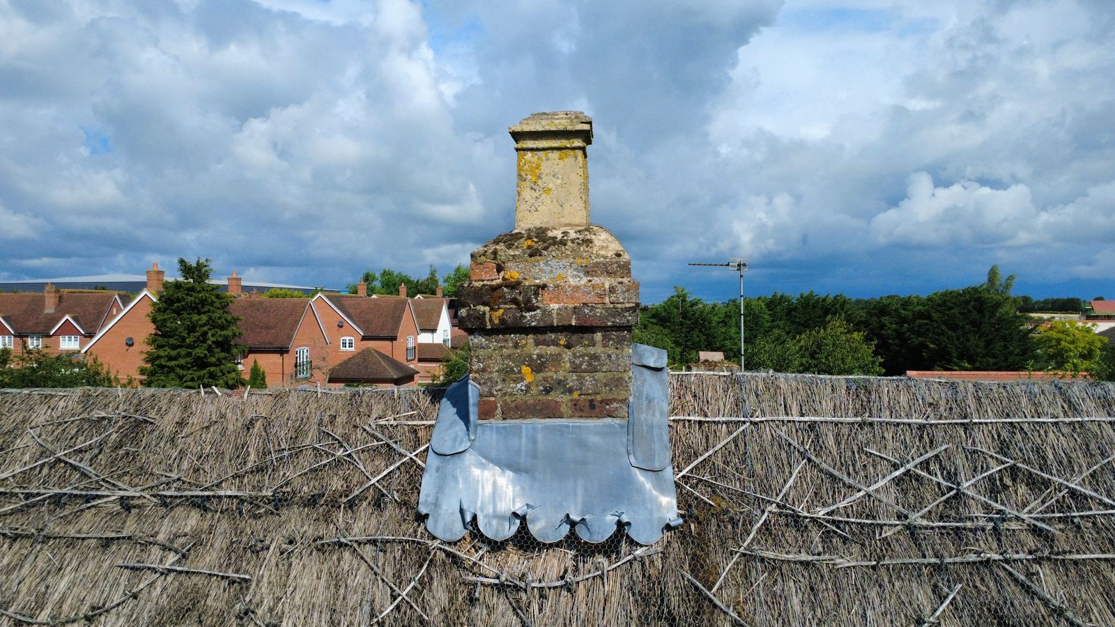 Drone view of a chimney and lead flashing on a thatched roof, photo 1 of 2