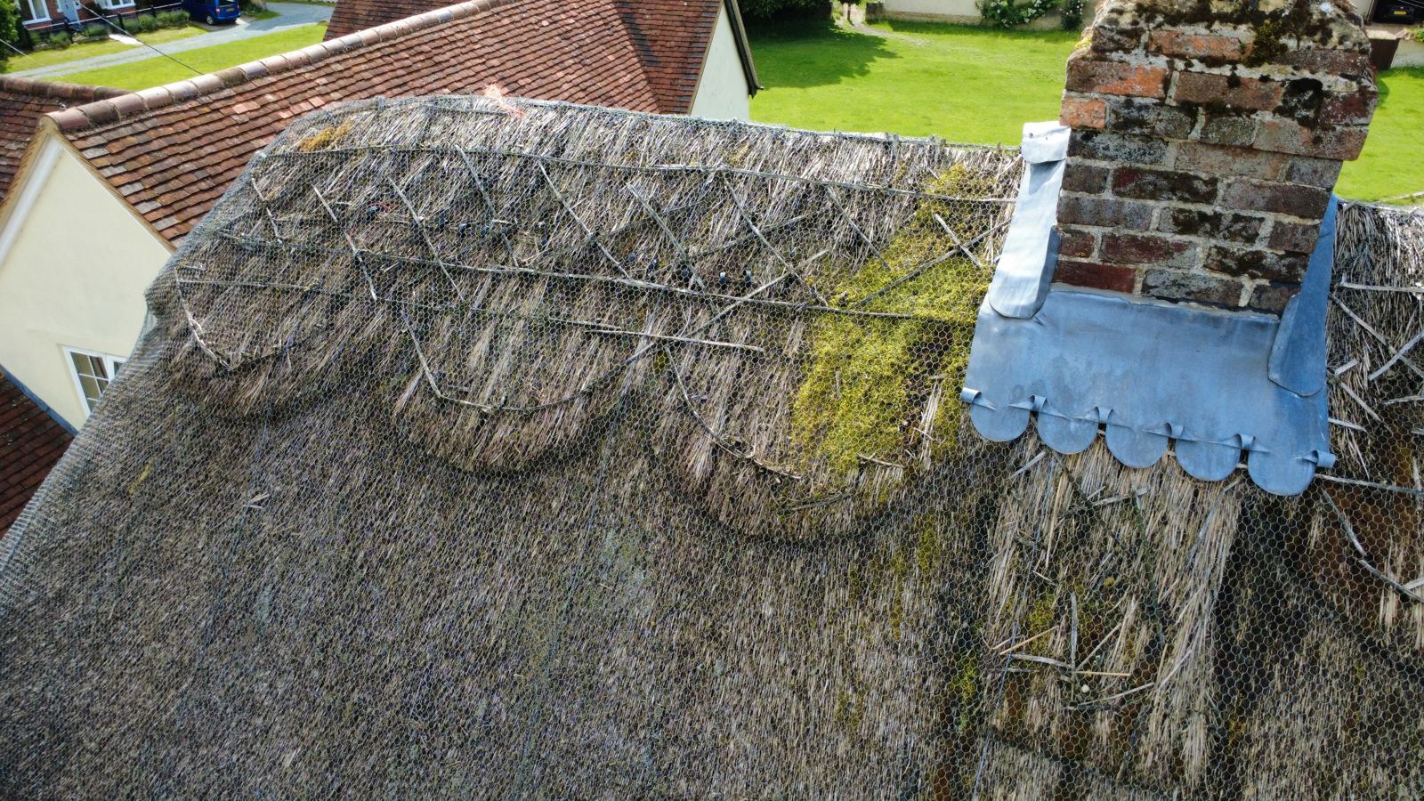 Worn thatch ridge with exposed liggers, moss growth and a lead chimney apron, photo 2 of 2