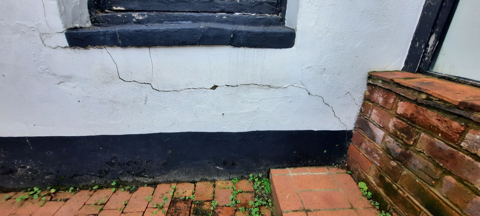 Cracked render above a damp-proof course beside steps, photo 1 of 2