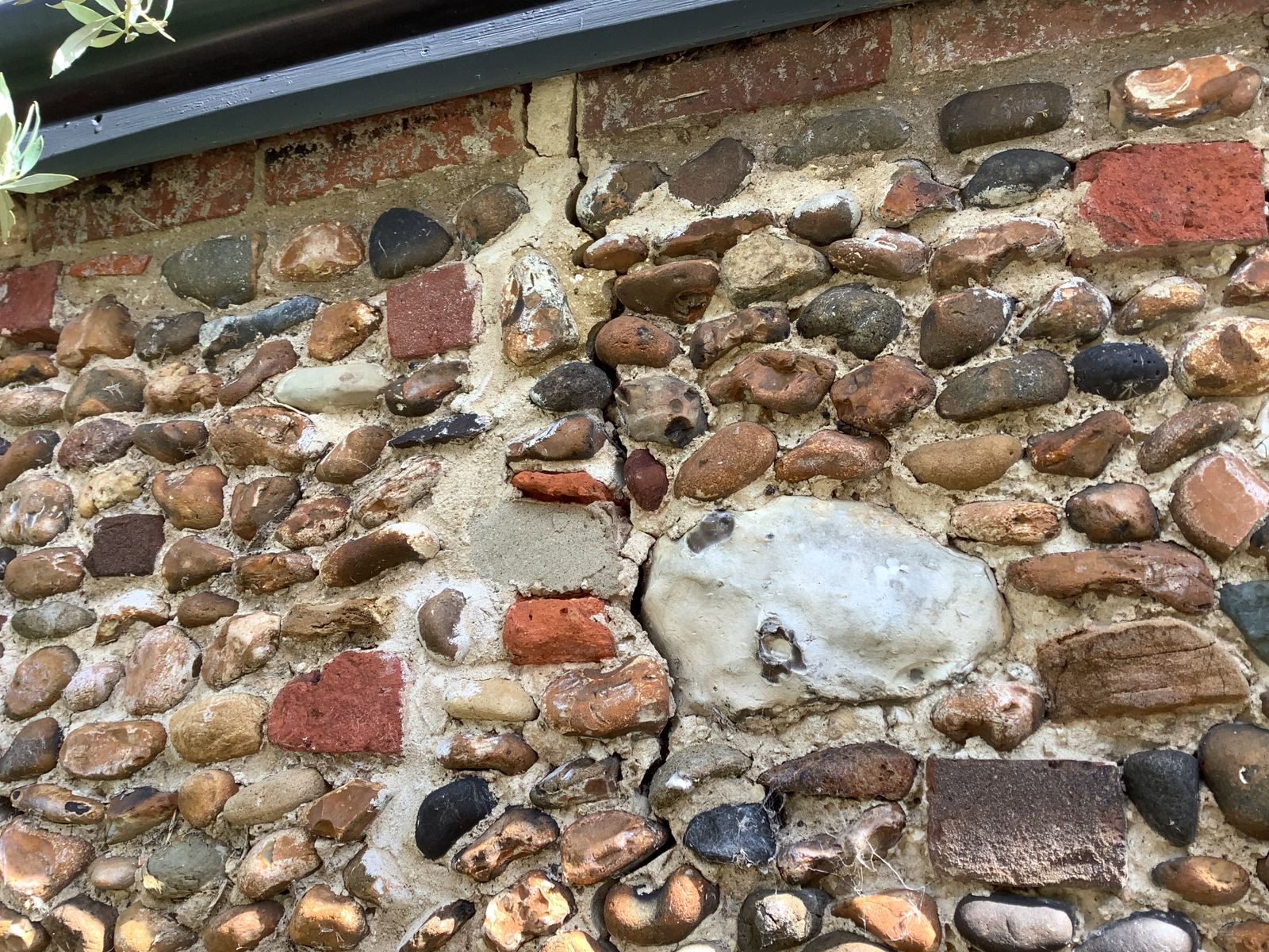 Flint and brick cobble wall with an old cement patch and eroded mortar, photo 2 of 4