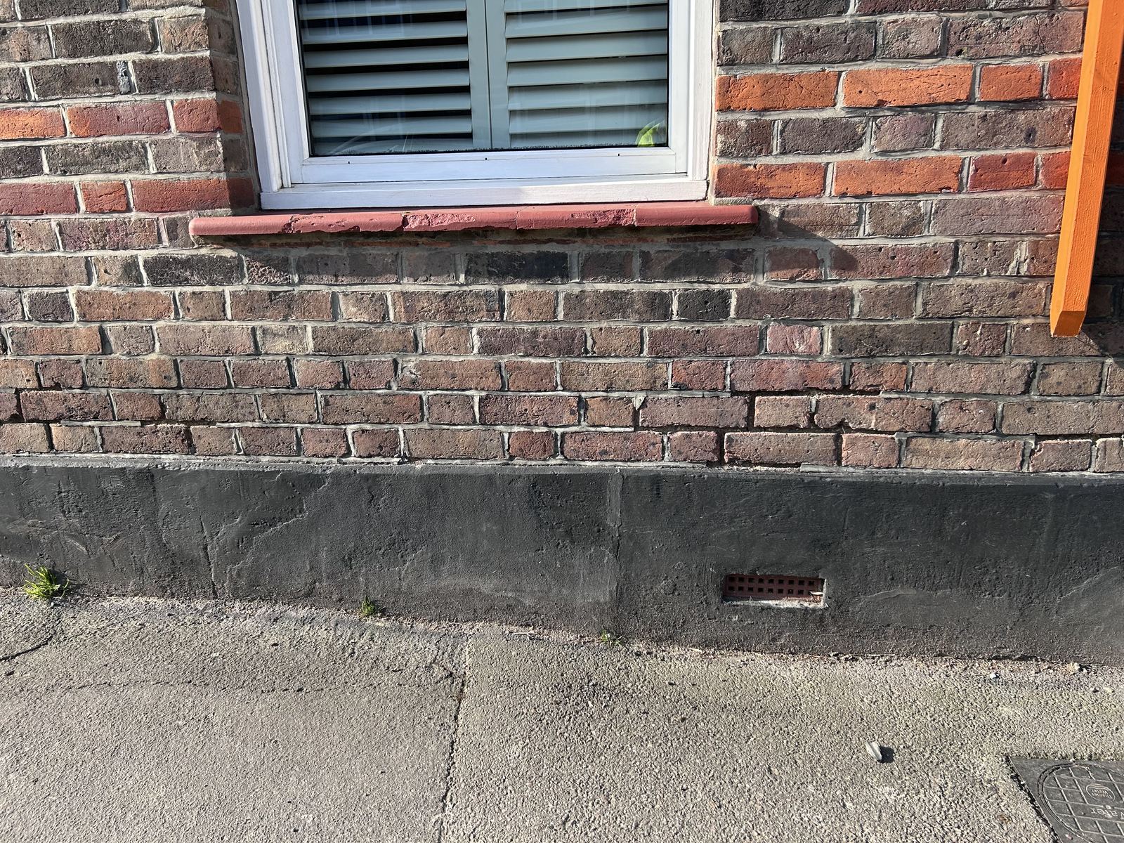 Brick wall and rendered plinth below a shuttered window, photo 1 of 4