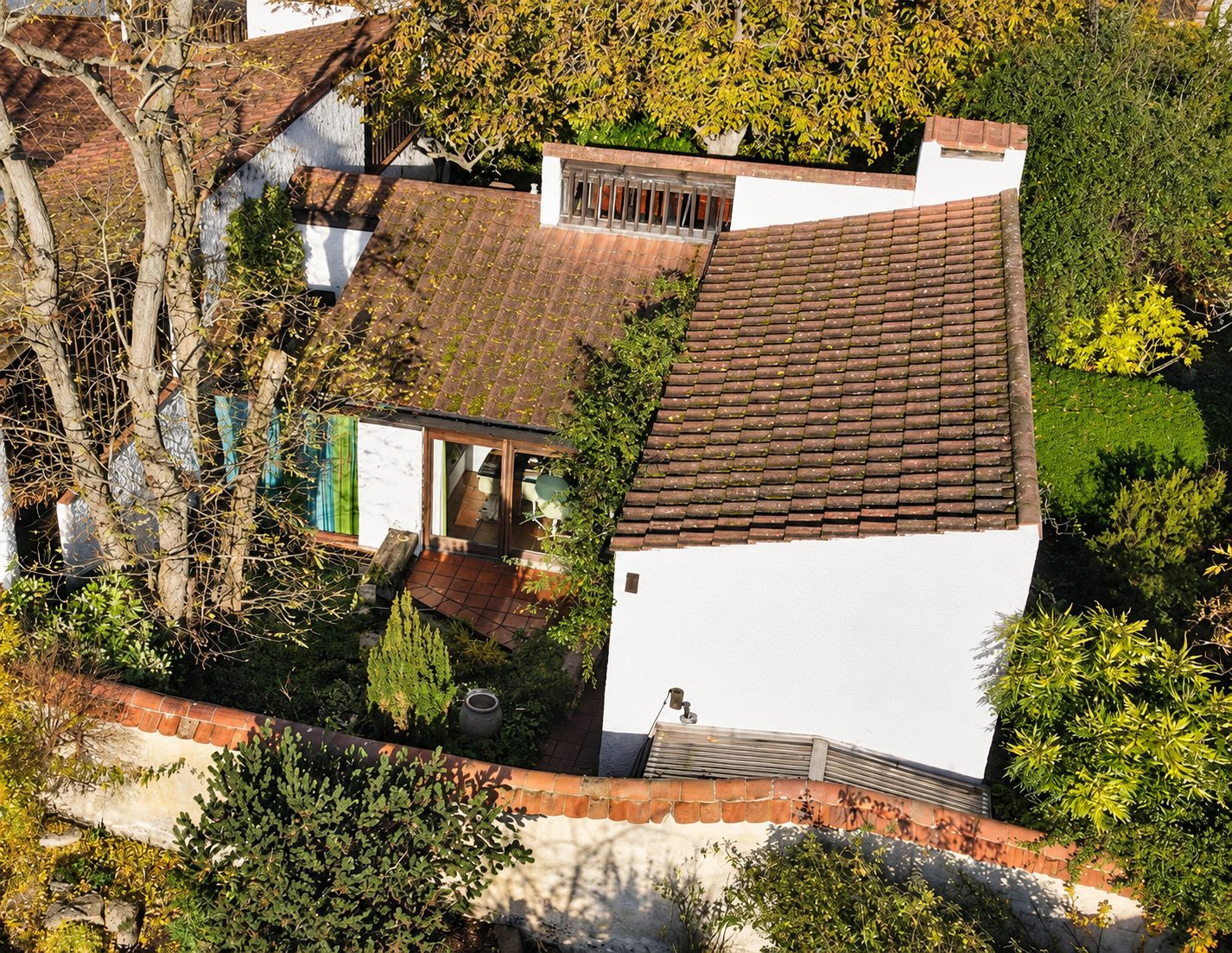 Aerial view of the white-rendered house with clay pantile roofs and a walled courtyard