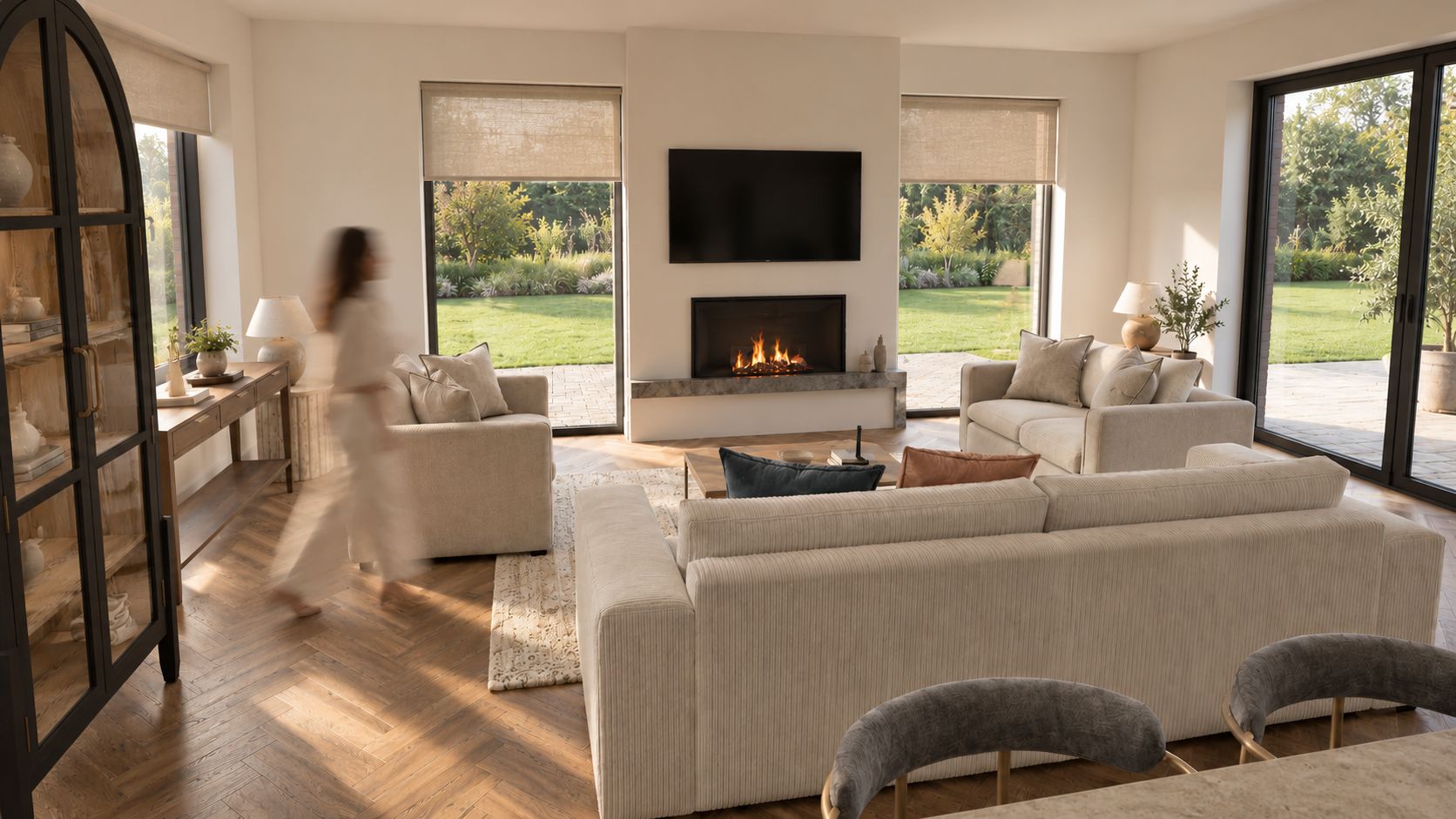Living room with a fireplace, cream sofas and full-height glazing to the garden, image 3 of 9
